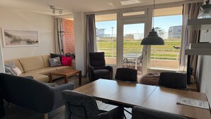 Un salon moderne comprenant un canapé, des fauteuils, une table basse et une table à manger.