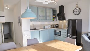 Une cuisine moderne avec des meubles de couleur bleu clair, un réfrigérateur noir et une table à manger en bois.