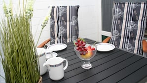 A dining table with a pitcher, plates, and a fruit bowl.