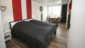 A bedroom with a bed, a nightstand, a desk, and a chair.