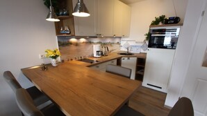 Une cuisine moderne avec une table à manger en bois, des placards blancs et un four encastré.