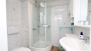 Une salle de bain avec une douche à parois de verre, un lavabo blanc et des toilettes.