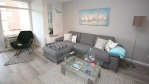 Un salon moderne avec un canapé gris, une table basse en verre et un fauteuil vert.