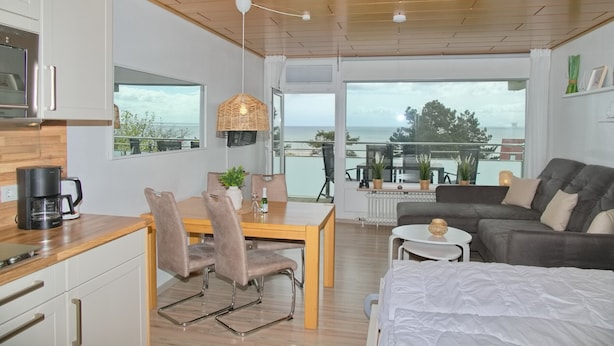 A modern living space with a dining area, kitchen, and seating area with a view of the sea. - Fürstenhof App. 430 mit Meerblick und Wlan (Grömitz)