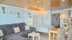 A modern living room with a grey sofa, a small round table, and a dining area with chairs. - Fürstenhof App. 430 mit Meerblick und Wlan (Grömitz)