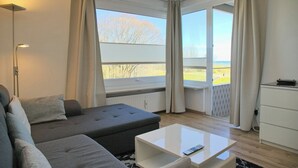 Een moderne woonkamer met een grijze bank, een witte salontafel en uitzicht op een balkon.
