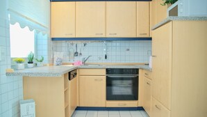 A kitchen with wooden cabinets, a built-in oven, and a countertop with various kitchen items. - Goldene Ruh App. 103 Inkl. Wlan (Grömitz)