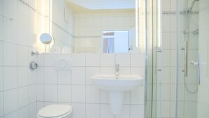 A bathroom with a toilet, sink, and glass shower enclosure. - Goldene Ruh App. 103 Inkl. Wlan (Grömitz)