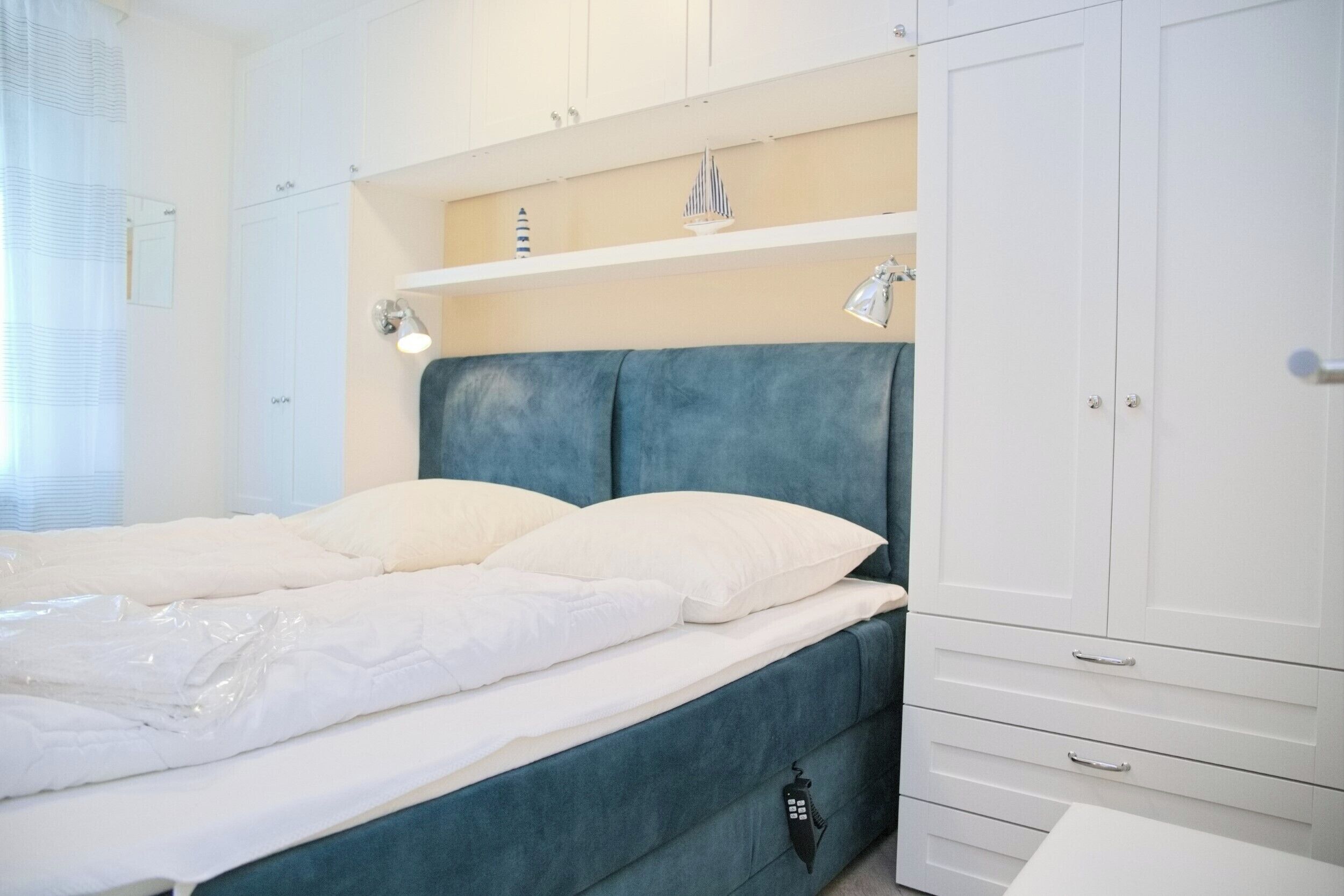 Un dormitorio con cama, armario y estante decorativo.