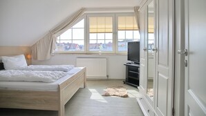 A bedroom with a bed, a radiator, a television, and a wardrobe. - Möwenstraße Haus 1 Inkl. Wlan (Grömitz)