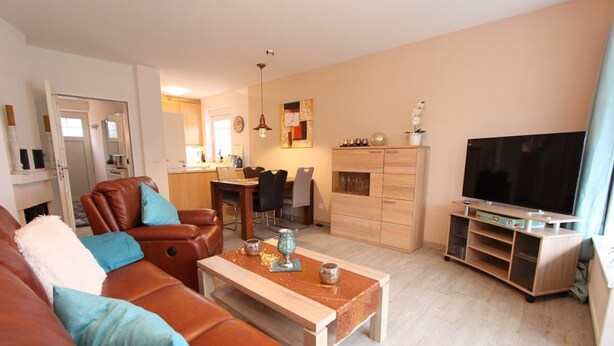 A living room with a brown leather sofa, a wooden coffee table, and a television on a wooden stand. - Möwenstraße Haus 1 Inkl. Wlan (Grömitz)