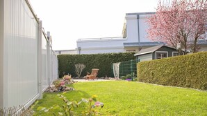A residential backyard with a lawn, a wooden chair, a hedge, and a house in the background. - Möwenstraße Haus 1 Inkl. Wlan (Grömitz)