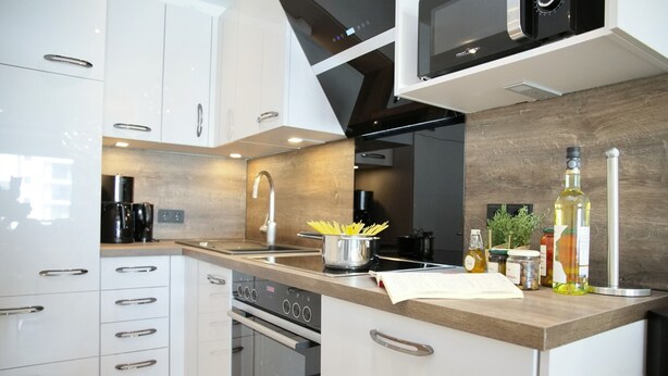 Una cocina moderna con armarios blancos, electrodomésticos de acero inoxidable y encimera de madera.