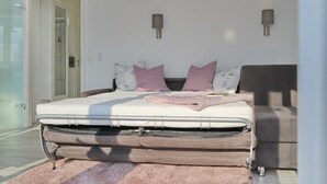 Quarto com cama, almofadas, mesa de cabeceira e luminárias fixadas na parede.
