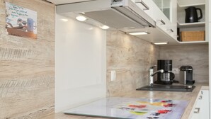 Uma cozinha moderna com painel de parede de madeira, uma cafeteira e uma ilha com bancada de vidro.