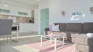 Uma cozinha moderna com armários brancos e uma área de jantar com mesa de vidro e tapete rosa.