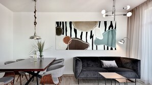 Ein modernes Wohnzimmer mit einem Esstisch, grauen Sofas und einem großen, abstrakten Gemälde an der Wand.