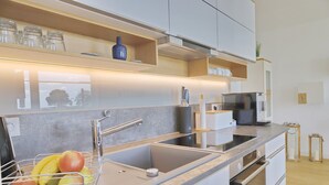 A modern kitchen with a stainless steel sink, a fruit basket, and a microwave. - Sealoft THE ONE Inkl. Wlan (Grömitz)