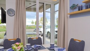 A dining area with a table set for two, a clock on the wall, and a view of the outside. - Sealoft THE ONE Inkl. Wlan (Grömitz)