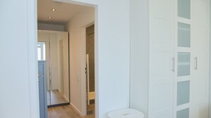 A hallway with a mirrored closet door, a white trash bin, and a wooden floor. - Tannenburg 505 Inkl. Wlan (Grömitz)