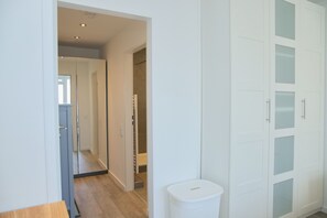 A hallway with a mirrored closet door, a white trash bin, and a wooden floor. - Tannenburg 505 Inkl. Wlan (Grömitz)