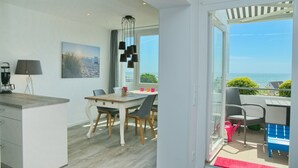 A modern kitchen with a dining area, large windows, and a view of the sea. - Tannenburg App. 508 Inkl. Wlan (Grömitz)