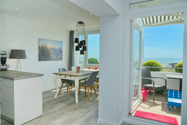 A modern kitchen with a dining area, large windows, and a view of the sea. - Tannenburg App. 508 Inkl. Wlan (Grömitz)