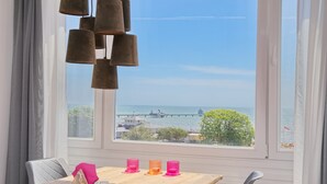 A dining area with a wooden table, three candles, and a view of the sea and pier. - Tannenburg App. 508 Inkl. Wlan (Grömitz)