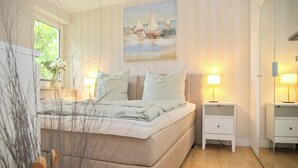 Un dormitorio con cama, mesitas de noche, tocador, un espejo y un cuadro en la pared.
