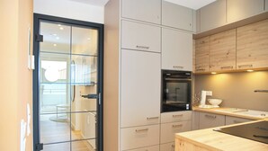 Una cocina moderna con puerta de vidrio que da a un comedor, electrodomésticos integrados y encimera de madera.