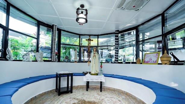 A room with a curved blue bench seating area, a central altar, and a patterned rug. - Blue Veil Villa (Kigali)