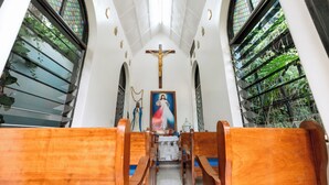 A church interior with wooden pews, a crucifix, and a religious painting. - Blue Veil Villa (Kigali)