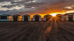 A row of beach huts with a wooden deck in front, under a sunset sky. - Gensing Lodge A Beautiful 3 Bedroom Boutique. Award Winning!  (Saint Leonards)