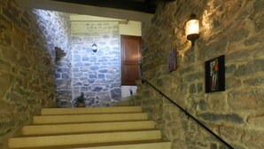 A stone staircase leading to a room with a wooden door and a wall-mounted light fixture. - Gîte Cévennes: Piscine, Lamas, Rivière (Cros)