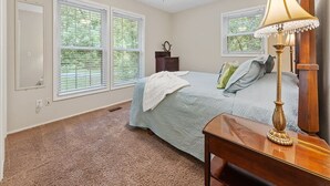 A bedroom with a bed, a desk, a lamp, a ceiling fan, and two windows. - Blue on Basildon (Bella Vista)
