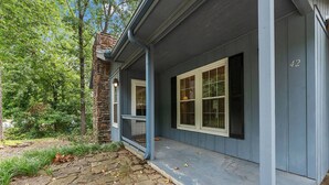 A house with a stone chimney, a porch with a railing, and a number '42' on the wall. - Blue on Basildon (Bella Vista)