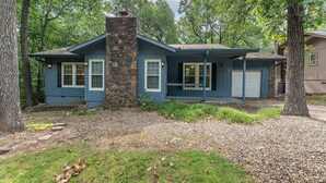 A two-story house with a stone chimney, blue siding, and a front porch. - Blue on Basildon (Bella Vista)