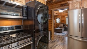 Una cocina con estufa, horno y microondas de acero inoxidable, armarios de madera y vistas a una zona de estar.