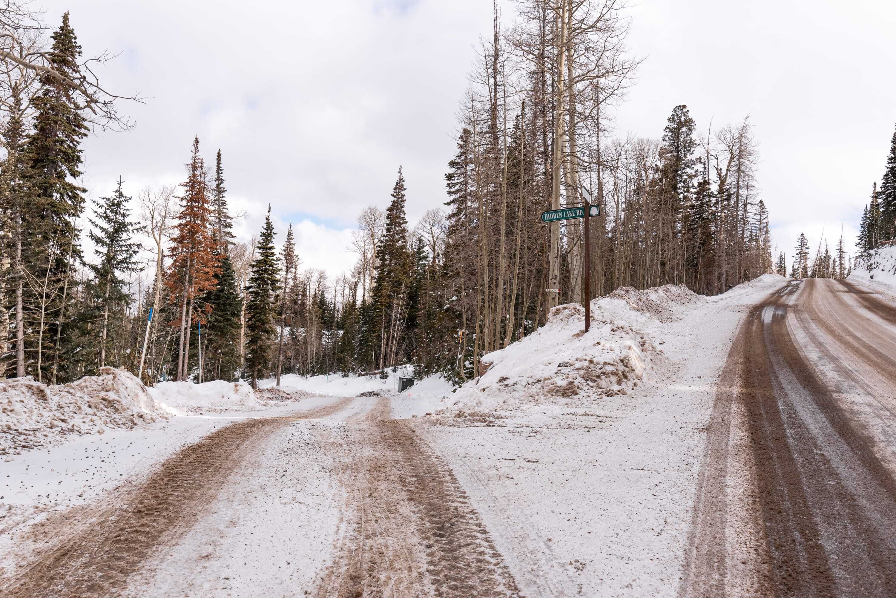 A snow-covered road with a sign for Hidden Lake Rd.