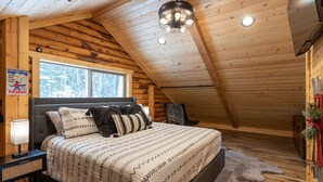 Un dormitorio tipo cabaña de madera con una cama, una ventana, una lámpara y un cartel sobre esquí.