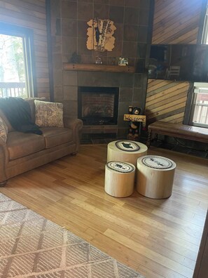 A cozy living room with a fireplace, a sofa, and three wooden ottomans. - Ski-In/Out Mountain Condo near Navajo Lodge, (Brian Head)