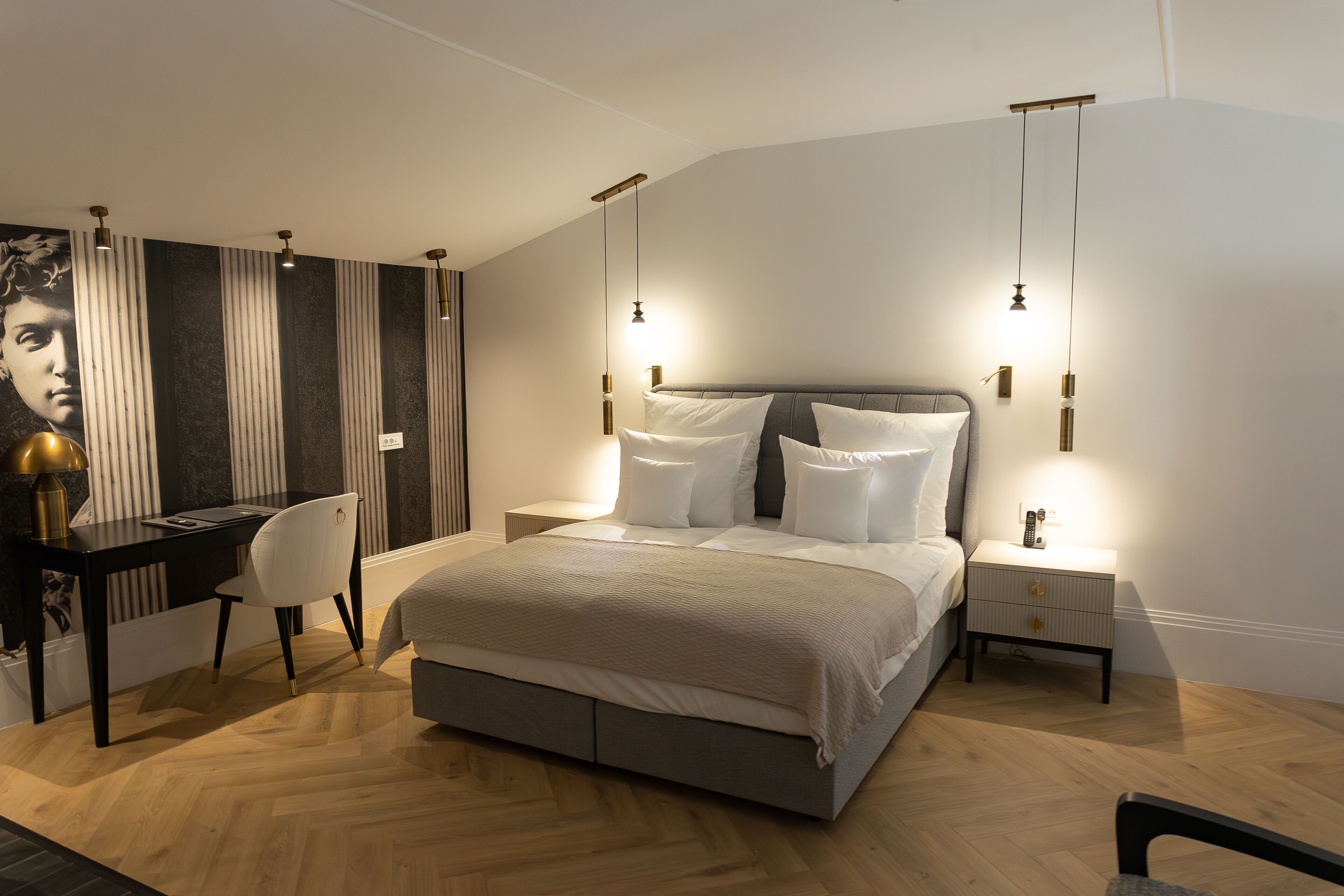 Un dormitorio moderno con una cama grande, mesitas de noche, un escritorio y una silla.
