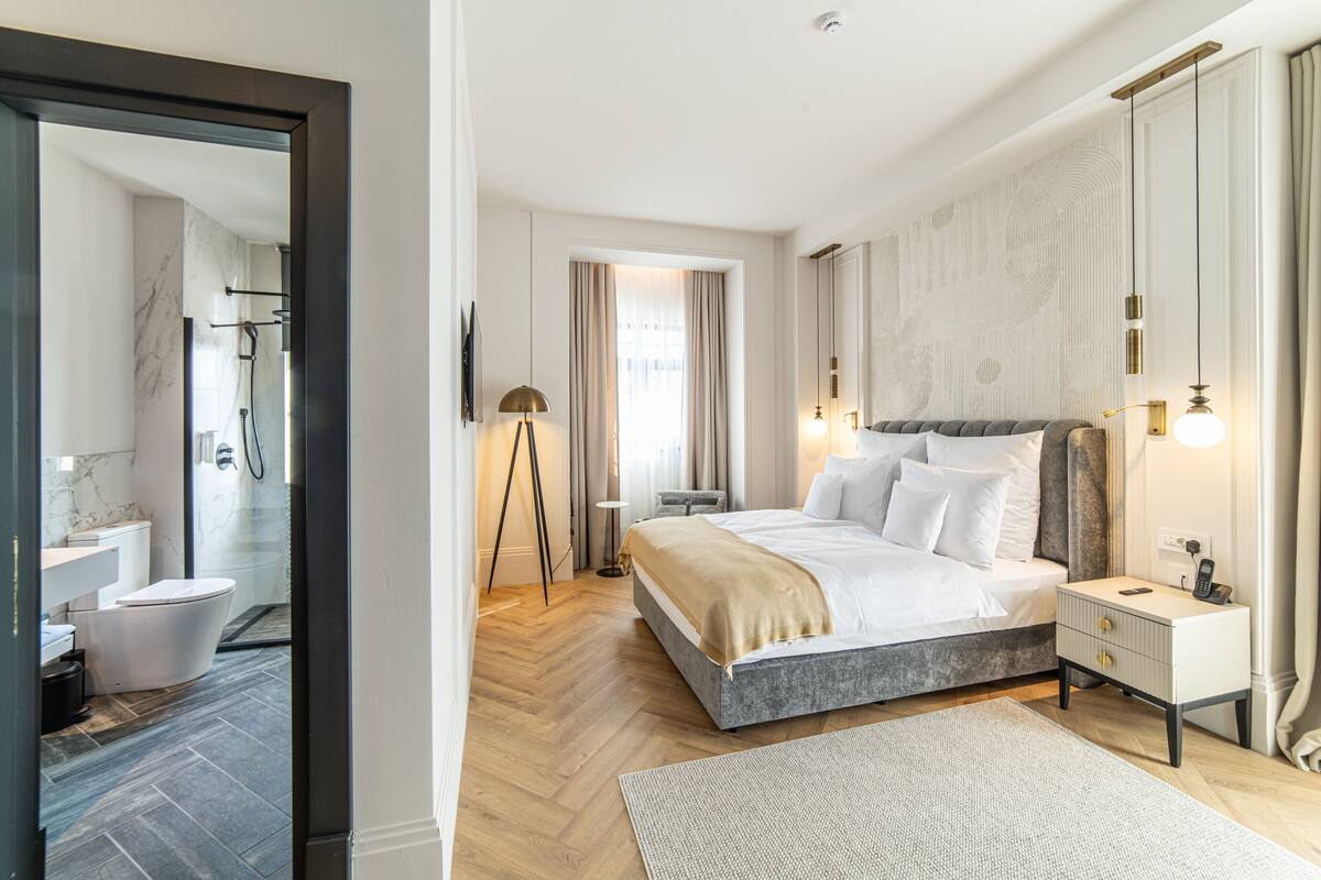 A modern hotel room with a large bed, bedside table, and a view of the bathroom.