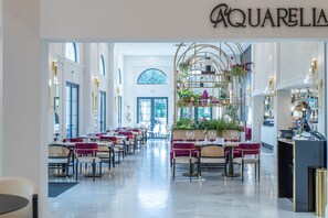 Un amplio vestíbulo de hotel con una zona de estar central, una recepción y un gran ventanal que proporciona luz natural.
