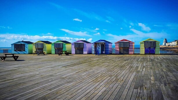 Un passeig de fusta amb cabanes de platja de colors alineades en fila.
