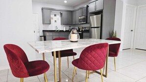 A modern kitchen with a marble table, red velvet chairs, and stainless steel appliances. - Beautiful apartment 9 min to Mercedes outlets (Weslaco)