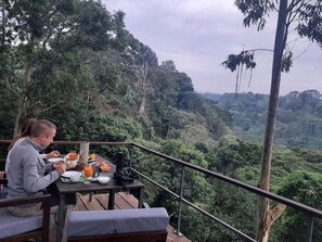 A dining area with a table set for two, overlooking a lush forested landscape. - E.Stay  (Moshi)