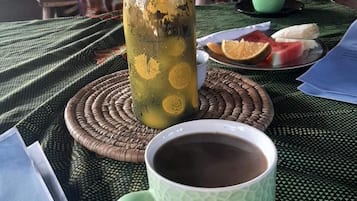 A table with a bottle, a cup, and a plate with fruit. There are papers and a smartphone on the table.