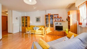 Un soggiorno con divano, tavolino, televisore e mobili in legno.