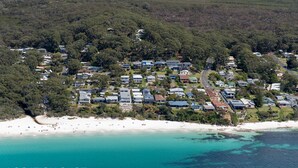 Vista aérea de una zona residencial costera con casas, una playa y aguas azules cristalinas.